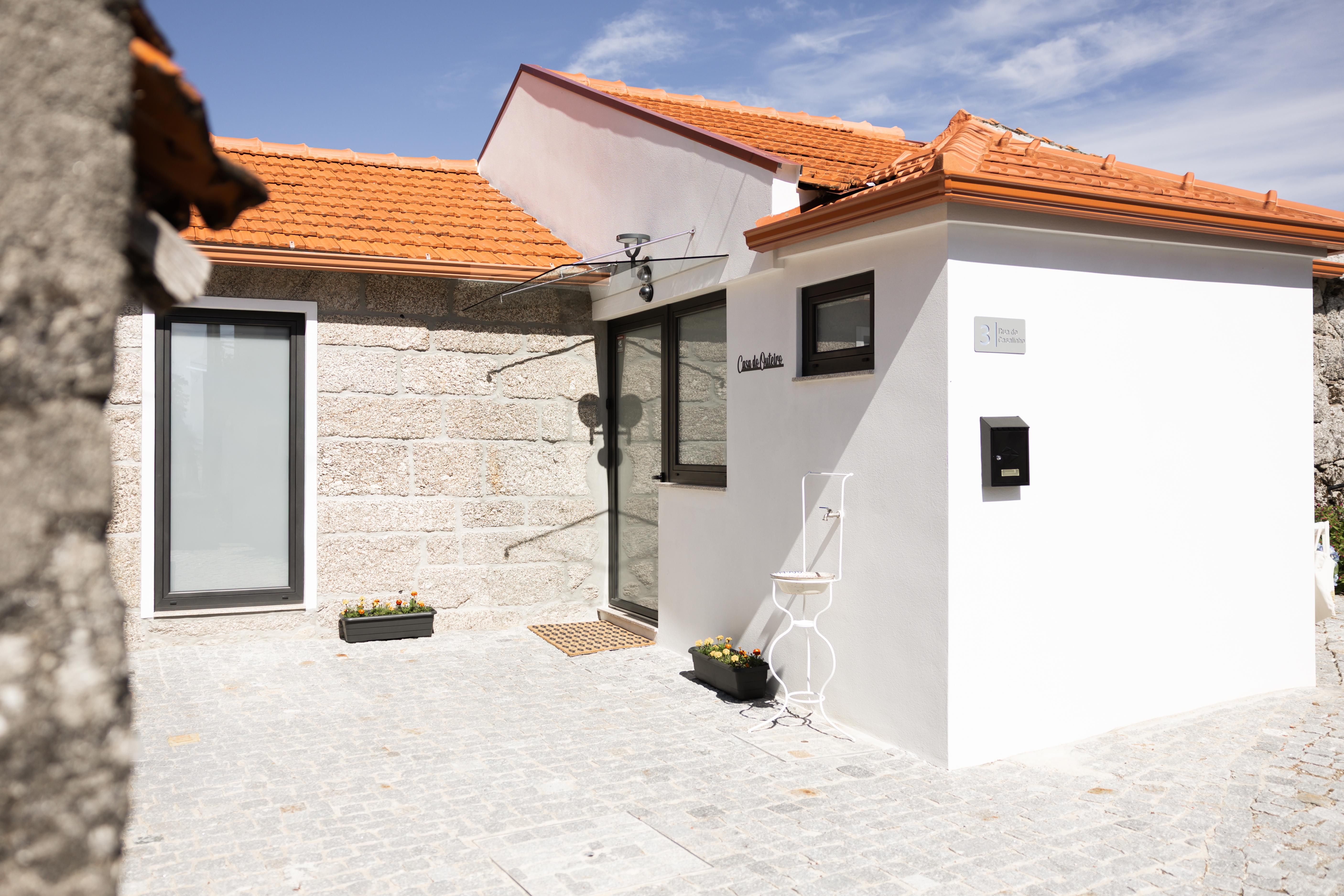 Entrada da Casa do Outeiro, com pátio em calçada, paredes de granito e cal branca